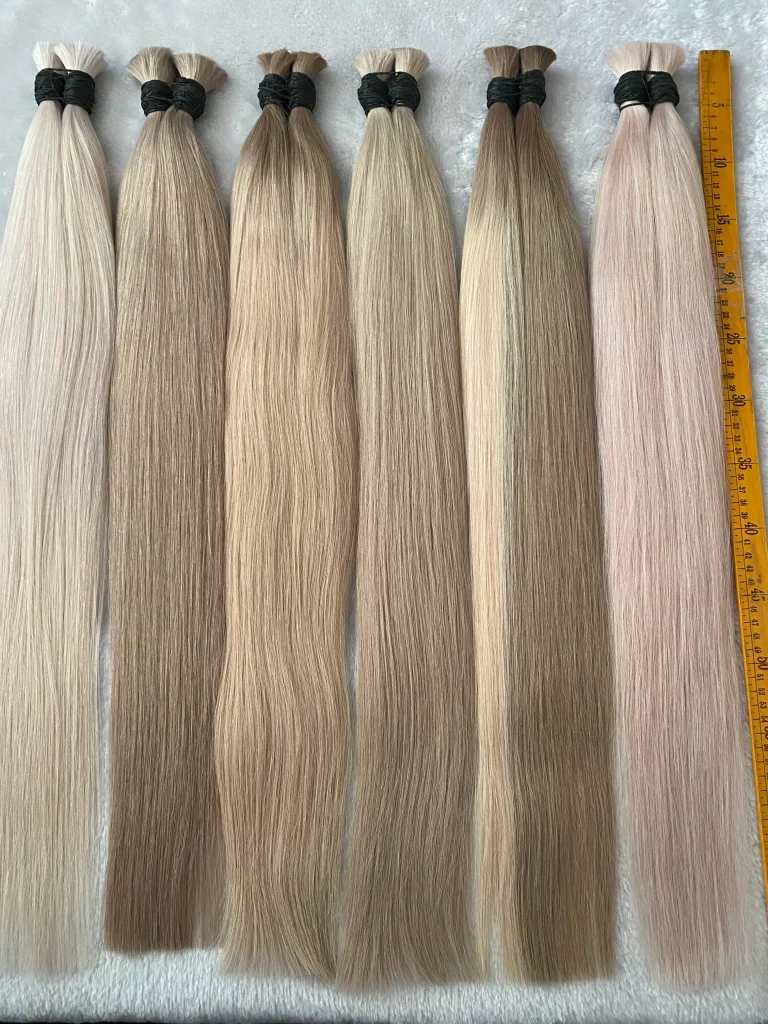 Straight blonde bulk hair bundles beside a measuring tape